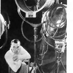 Buster Keaton w atelier filmowym, otoczony wielkimi reflektorami