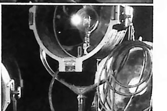 Buster Keaton w atelier filmowym, otoczony wielkimi reflektorami