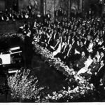 Sala koncertowa pełna publiczności, przy fortepianie i estradzie występ Jana Kiepury w Berlinie w 1935 roku.