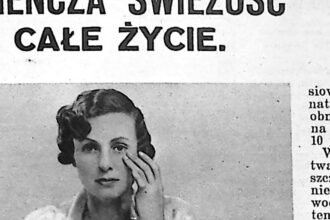 Kobieta w jasnym szlafroku siedzi przed lustrem przy toaletce z przyborami kosmetycznymi.