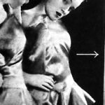 Młoda kobieta w krótkim kostiumie balowym przegląda się w lustrze, zdjęcie inscenizowane z 1935 roku.