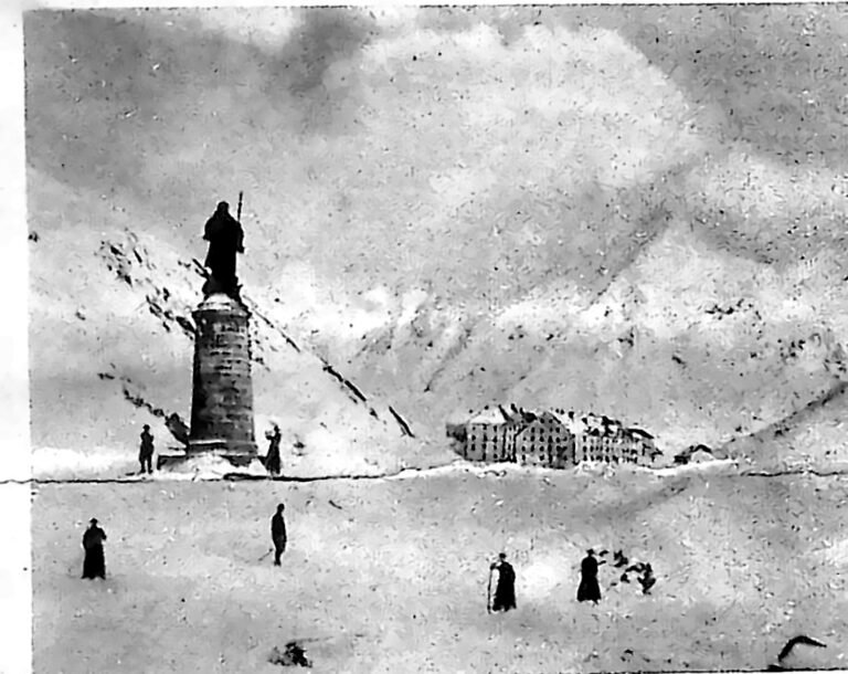 Zaśnieżona przełęcz św. Bernarda z posągiem świętego na cokole i budynkiem klasztoru w tle. Fotografia z 1926 r.