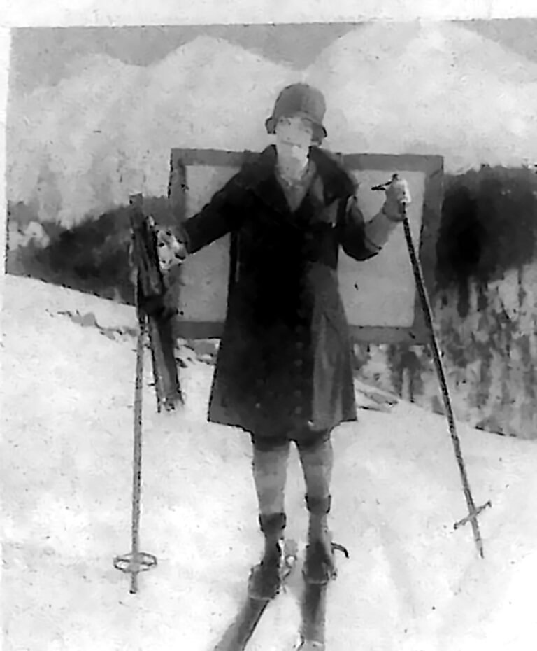 Kobieta na nartach, w kapeluszu i płaszczu, z blejtramem przytroczonym do pleców, na śniegu w St. Moritz. Fotografia z 1926 r.