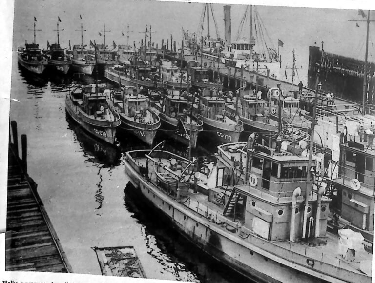 Kilkanaście kutrów straży przybrzeżnej zacumowanych rzędem w przystani w Bostonie. Fotografia z 1926 r.