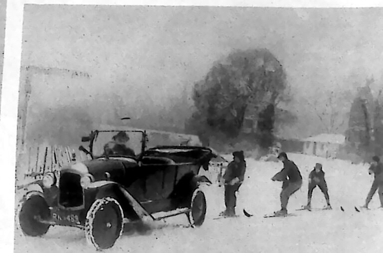 Otwarty samochód ciągnący po śniegu kilkoro narciarzy nad Tamizą pod Windsorem. Fotografia z 1926 r.