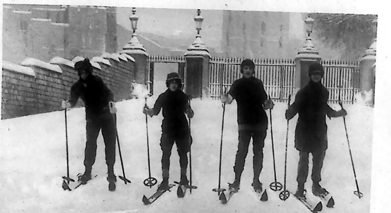 Czterech narciarzy z kijkami, ustawionych na śniegu przed murem zamku Windsor. Fotografia z 1926 r.
