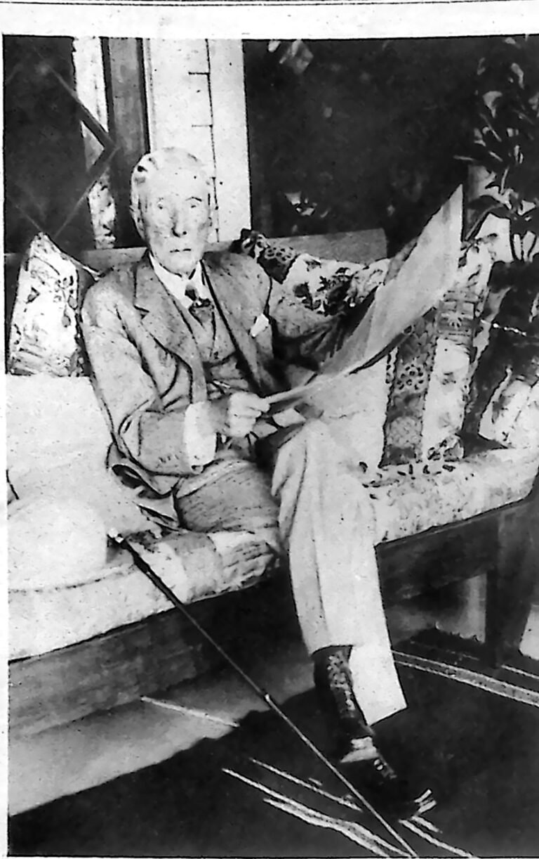 Sędziwy John D. Rockefeller w jasnym ubraniu, siedzący w fotelu z gazetą. Fotografia z 1926 r.