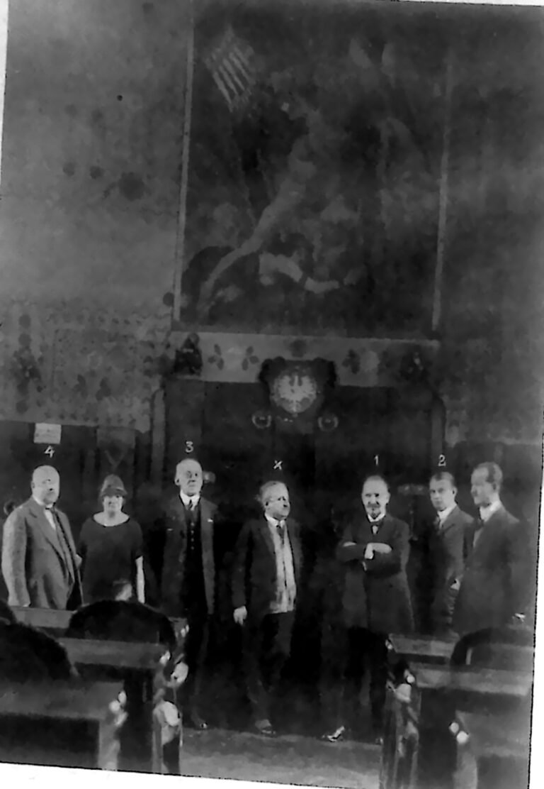 Grupa mężczyzn i jedna kobieta w reprezentacyjnej sali krakowskiej Izby Handlowej. Fotografia z 1926 r.