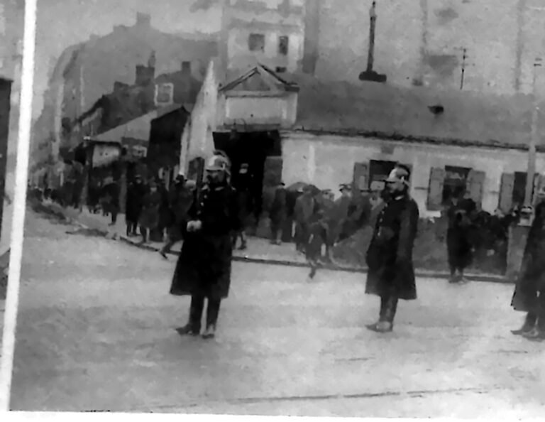 Grupa policjantów w płaszczach i hełmach na ulicy warszawskiej dzielnicy Wola. Fotografia z 1926 r.
