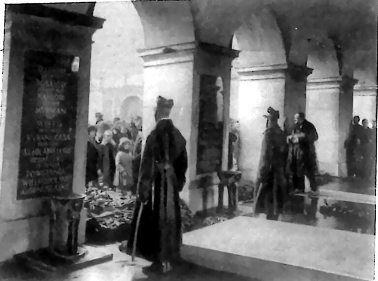 Wartownicy w mundurach obejmujący straż honorową przy Grobie Nieznanego Żołnierza w Warszawie, wśród wieńców. Fotografia z 1926 r.