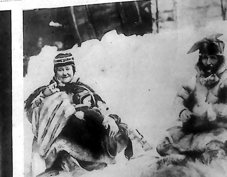 Rodzina eskimoska w futrzanych parkach, siedząca na śniegu przed namiotem. Fotografia z 1926 r.