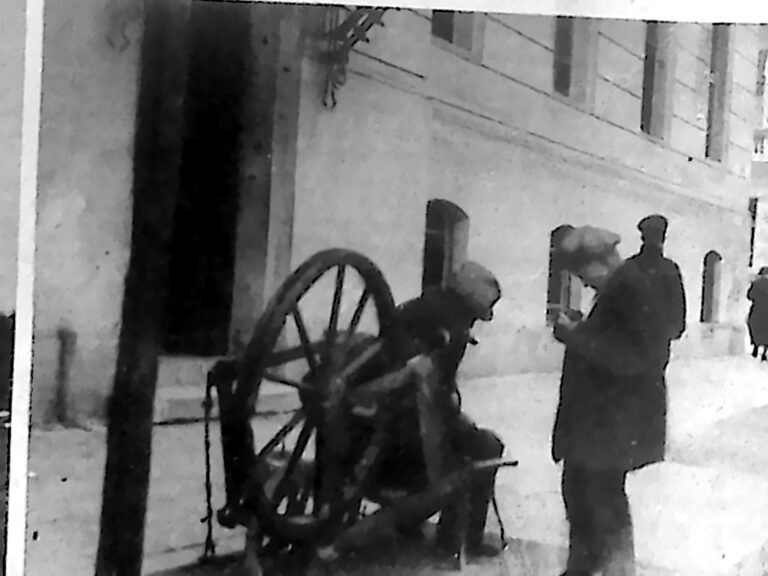 Wędrowny szlifierz przy kole tocznym na chodniku przed Domem Akademickim w Krakowie, obok przechodzień. Fotografia z 1926 r.