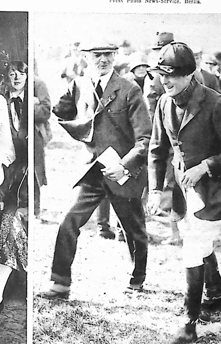 Książę Walii w stroju jeździeckim i kasku rozmawiający z mężczyzną w płaszczu na torze wyścigowym. Fotografia z 1926 r.