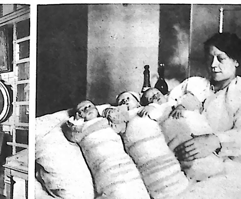 Matka w łóżku obok trojga niemowląt ułożonych rzędem w powijakach. Fotografia z 1926 r.