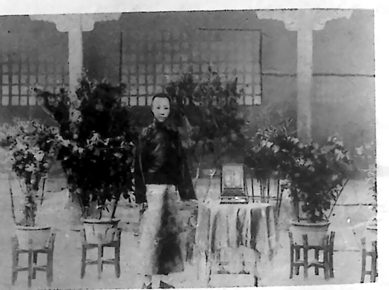 Młody cesarz Pu Yi stojący w jasnym stroju w oranżerii swojej rezydencji w Tiencinie. Fotografia z 1926 r.