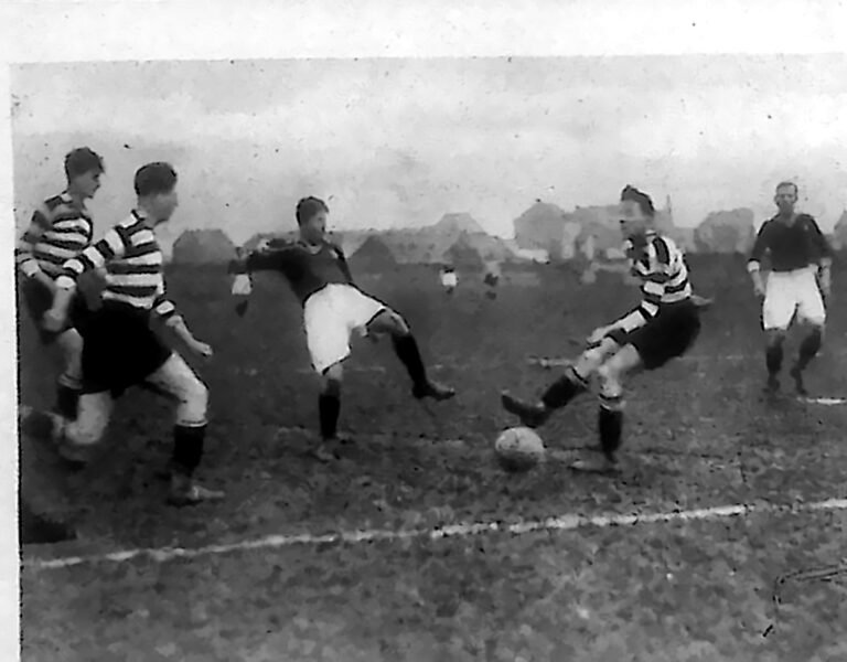 Piłkarze w paskowanych i ciemnych koszulkach w walce o piłkę na boisku. Fotografia z 1926 r.