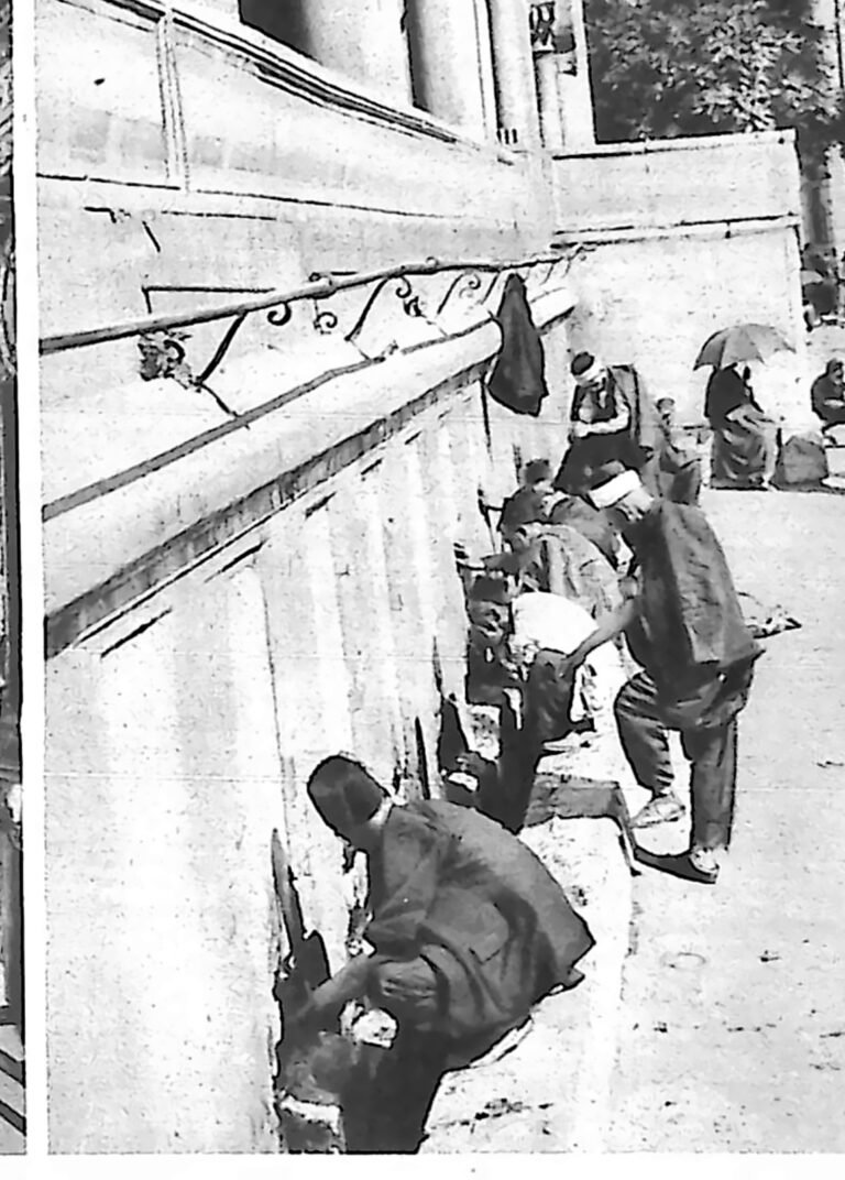 Mężczyźni dokonujący obmyć przy kranach pod ścianą meczetu. Fotografia z 1926 r.