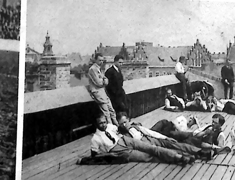 Studenci opalający się na płaskim dachu Domu Akademickiego, w tle wieże krakowskich kościołów. Fotografia z 1926 r.