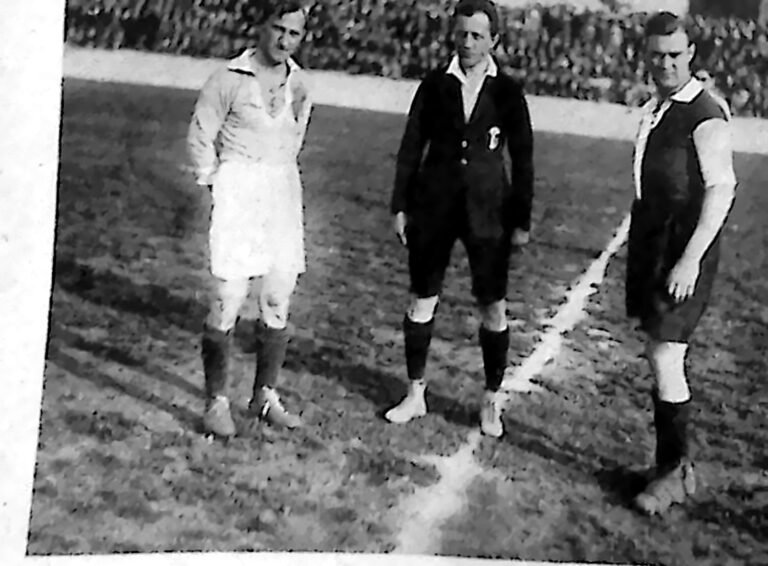 Dwaj kapitanowie drużyn i sędzia na środku boiska przed rozpoczęciem meczu. Fotografia z 1926 r.