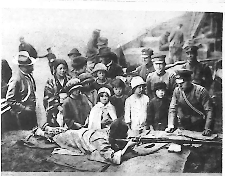 Japońskie dziewczęta ćwiczące strzelanie z karabinów w pozycji leżącej, obok oficerowie. Fotografia z 1926 r.