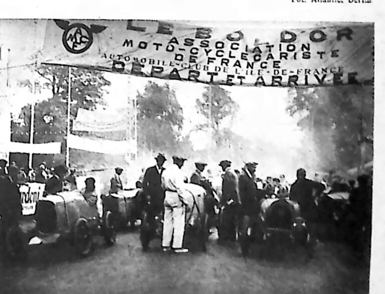 Samochody i publiczność pod bramą startową z napisem „Départ et arrivée” w Lasku Bulońskim. Fotografia z 1926 r.