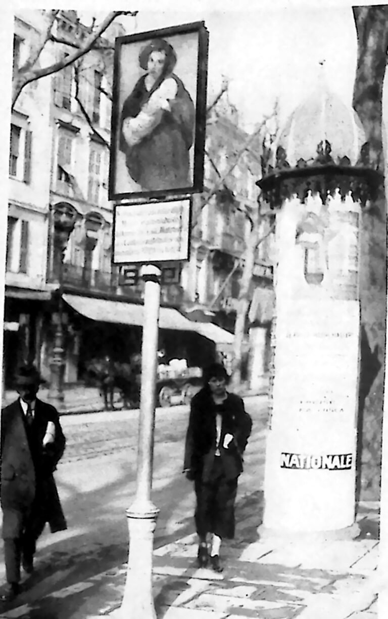 Uliczny słup w Nicei z obrazem Madonny i tablicą informacyjną, obok przechodnie. Fotografia z 1926 r.